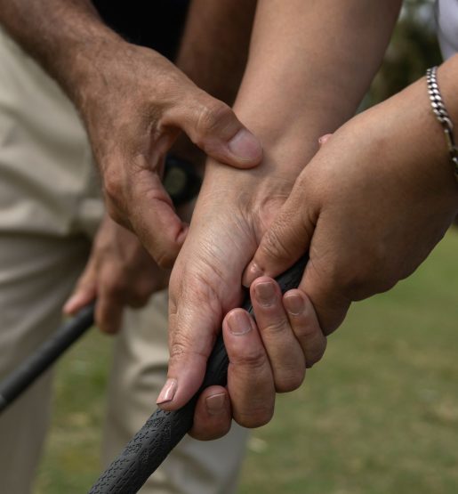 Closeup of the hands of people on a golf course, holding a golf club in one hand and gesturing